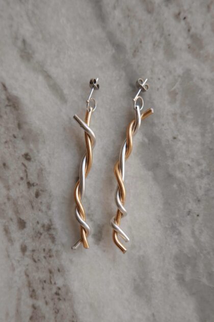 ADI twisted silver and gold drop earrings on marble